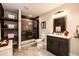 Modern bathroom with a dark vanity, a tile shower, and open shelving with baskets at 34942 Wagon Wheel Trl, Elizabeth, CO 80107