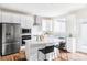 Bright kitchen features white cabinetry, stainless steel appliances, island with bar seating, and light countertops at 11488 E 25Th Dr, Aurora, CO 80010