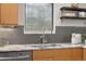 Close-up of kitchen sink with gray backsplash, marble countertop, and natural wood cabinets at 1295 Elm St, Denver, CO 80220