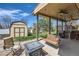 Outdoor covered patio with a swing, ceiling fan, grill, and a small shed on the green lawn at 2023 S Rifle St, Aurora, CO 80013