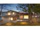 Charming two-story home with brick accents, lush lawn, mature trees, and warm exterior lighting at dusk at 3930 S Argonne Way, Aurora, CO 80013