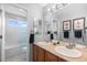 Bright bathroom featuring a double vanity, framed mirror, and a bathtub with tiled walls at 5319 W Hoover Dr, Littleton, CO 80123