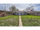 Shot of the house from the large backyard, lush green grass and a sidewalk leading to the home at 3075 Fairfax St, Denver, CO 80207