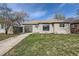 Exterior front view of single-story home with gray brick, green lawn and driveway leading to attached garage at 3075 Fairfax St, Denver, CO 80207