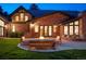 Backyard with a brick house, fire pit and outdoor furniture, well-manicured lawn and landscaping at dusk at 1328 E Layton Ave, Cherry Hills Village, CO 80113