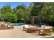 A brick patio with a fire pit, outdoor seating, green lawns and a pool behind a brick wall with lush plants at 1328 E Layton Ave, Cherry Hills Village, CO 80113