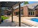 A backyard featuring an open air pergola with lights, a brick fireplace and lush landscaping surrounding a brick house at 1328 E Layton Ave, Cherry Hills Village, CO 80113