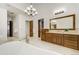 A spacious bathroom with wood vanity, large mirror and lighting fixture, and tile flooring at 1328 E Layton Ave, Cherry Hills Village, CO 80113