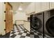 Well-lit laundry room with checkered floors and modern appliances at 1328 E Layton Ave, Cherry Hills Village, CO 80113