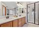 Bright bathroom featuring double sinks, a quartz countertop, and a glass-enclosed shower at 9375 S Hoyt Ct, Littleton, CO 80127