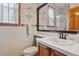 Bright bathroom featuring a vanity with tile countertops and a decorative mirror, and a toilet at 9375 S Hoyt Ct, Littleton, CO 80127