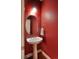 A charming powder room features a pedestal sink, oval mirror, and classic red paint at 2479 S High St, Denver, CO 80210