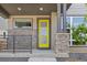 Welcoming front porch with stone accents, a yellow door, and modern railings enhance this home's curb appeal at 21482 E 60Th Ave, Aurora, CO 80019