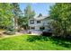 Expansive backyard featuring a large deck, lush lawn, mature trees, and a hot tub at 2397 Hearth Dr, Evergreen, CO 80439