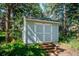 A well-maintained shed with steps, offering ample outdoor storage in a wooded setting at 2397 Hearth Dr, Evergreen, CO 80439