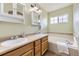 Well-lit bathroom with double sinks, spacious vanity, and a tub with a tile surround at 3912 Ute Mountain Trl, Castle Rock, CO 80109