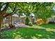 A backyard features a brick house with a patio and lots of green grass and trees at 675 Dahlia St, Denver, CO 80220