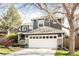 Stunning curb appeal featuring a gray exterior, a white garage door, stone accents, and lush greenery at 5910 W Sumac Ave, Littleton, CO 80123