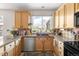 Bright kitchen features wood cabinets, a sink under a window, and granite countertops at 5910 W Sumac Ave, Littleton, CO 80123