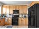 Well-lit kitchen with wood cabinets, black appliances, and tile backsplash at 5910 W Sumac Ave, Littleton, CO 80123