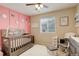 This Bedroom features pink paneling on the walls with flower accents, a crib and sitting chair at 4316 S Netherland St, Aurora, CO 80015