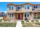 Charming townhouse with stone accents, a red door, and a cozy front porch with rocking chairs at 4316 S Netherland St, Aurora, CO 80015