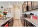 Galley kitchen featuring dark cabinets, stainless appliances, and stone countertops at 4316 S Netherland St, Aurora, CO 80015