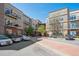 Beautiful condo complex with tan and brick facade, balconies, sidewalks, and parking on a sunny day at 5677 S Park Pl # A102, Englewood, CO 80111