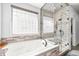 Bright bathroom featuring a soaking tub and glass-enclosed shower with tile surround at 2373 S Joyce St, Denver, CO 80228