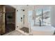 A bathtub and glass enclosed shower are in a bathroom with an arched doorway at 16685 Trail Sky Cir, Parker, CO 80134