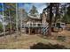 Exterior shot of the home featuring a large deck, brick chimney and treed lot at 5382 S Pine Rd, Evergreen, CO 80439