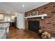 Open-concept living room with brick fireplace, hardwood floors, and adjacent modern kitchen at 5382 S Pine Rd, Evergreen, CO 80439