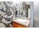 The stylish powder room features an eye-catching wallpaper and vessel sink at 471 N Jackson Gap Way, Aurora, CO 80018