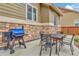 A blue grill sits next to a stone-clad wall, adjacent to a dining table and chairs at 471 N Jackson Gap Way, Aurora, CO 80018