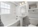 Well-lit bathroom features a tiled tub/shower combo, pedestal sink, and ample natural light from a window at 2872 Jasmine St, Denver, CO 80207