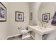 A stylish powder room featuring a pedestal sink, oval mirror, and decorative artwork at 2905 Morningbird Ln, Castle Rock, CO 80109
