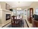Cozy dining room with fireplace, chandelier, wood table, and sun-filled bay windows at 22166 E Chestnut Pl, Aurora, CO 80016