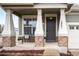 Inviting front porch with stone accents, a bench, and a stylish front door at 5861 Mt Shadows Blvd, Firestone, CO 80504