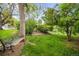 Lush backyard featuring mature trees, a park bench, and a grassy area perfect for recreation and relaxation at 9045 W Ithaca Pl, Denver, CO 80235
