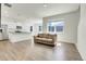 Open-concept living room with wood floors that connects to a bright kitchen and dining area at 45840 Laceleaf Dr, Bennett, CO 80102