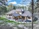 Aerial view of a luxury home in a wooded setting, featuring a patio, hot tub, and lush green landscape at 18330 Archers Dr, Monument, CO 80132
