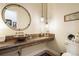 Stylish bathroom featuring a vessel sink, wood countertop, decorative lighting, and a round mirror at 18330 Archers Dr, Monument, CO 80132
