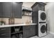 Well-lit laundry room featuring shaker cabinets, white countertop, patterned tile floor, and stacked washer and dryer at 18330 Archers Dr, Monument, CO 80132