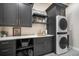 Well-appointed laundry room features modern cabinetry, floating shelves, and a stacked washer/dryer at 18330 Archers Dr, Monument, CO 80132