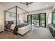 Bright main bedroom with a four-poster bed, a sitting bench, and a sliding glass door to the outside at 18330 Archers Dr, Monument, CO 80132