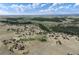 Expansive aerial view showcases the property's large acreage and private pond nestled among mature trees and rolling hills at 897 E Rim Rd, Franktown, CO 80116
