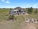 Aerial view of the home with a large lawn, fire pit, lush green trees and open plains at 897 E Rim Rd, Franktown, CO 80116
