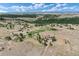 An aerial view of a single Gathering home on beautiful acreage with mature trees, and pond under a cloudy blue sky at 897 E Rim Rd, Franktown, CO 80116