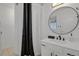 Clean bathroom features a modern vanity, round mirror, and a shower with black and white curtains at 897 E Rim Rd, Franktown, CO 80116