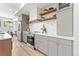 Contemporary kitchen featuring grey cabinets, stainless steel appliances, wooden shelves and light hardwood flooring at 1048 Knox Ct, Denver, CO 80204
